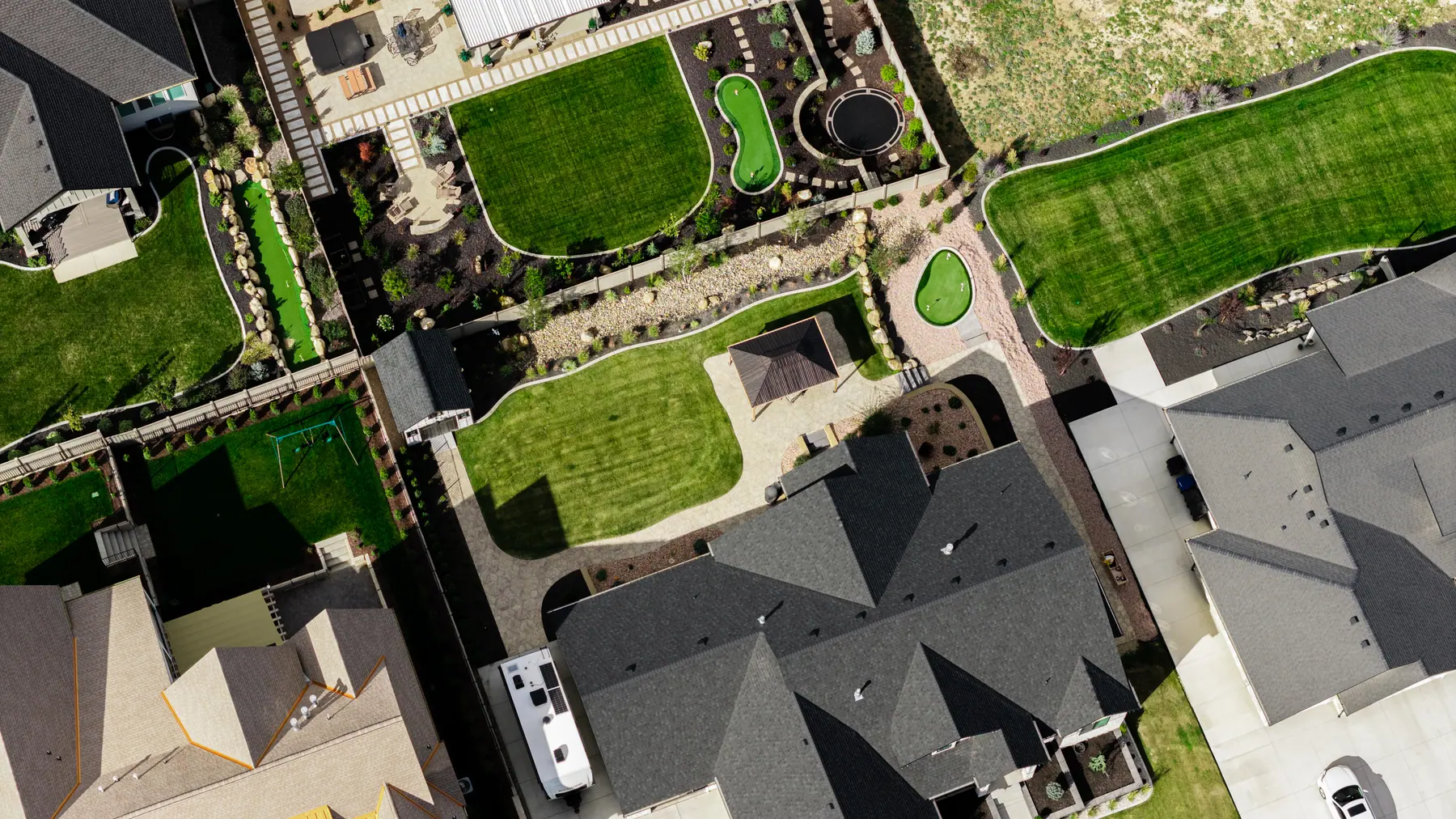 Backyard lawn and putting greens by J&H Landscaping in Utah County