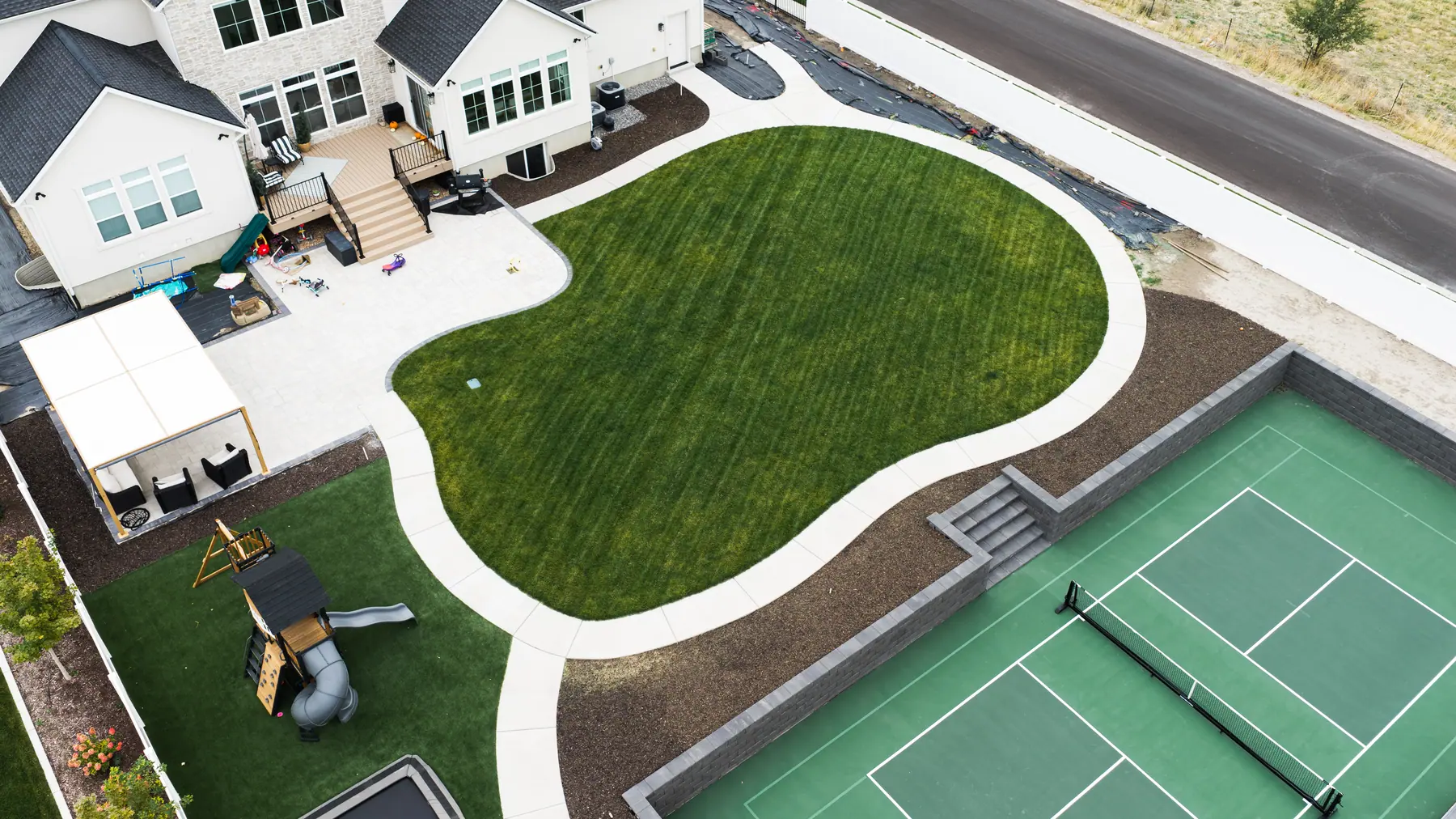 Curved lawn beside the court by J&H Landscaping in Mapleton
