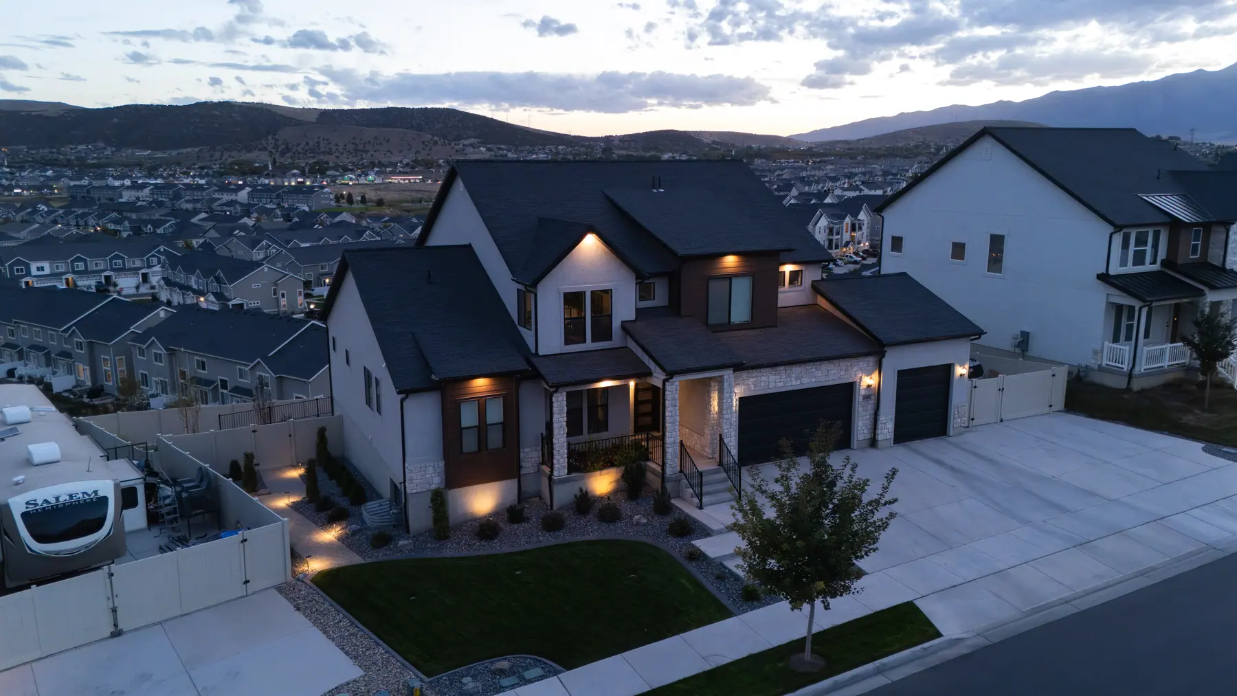 Front yard lit at dusk by J&H Landscaping in Saratoga Springs