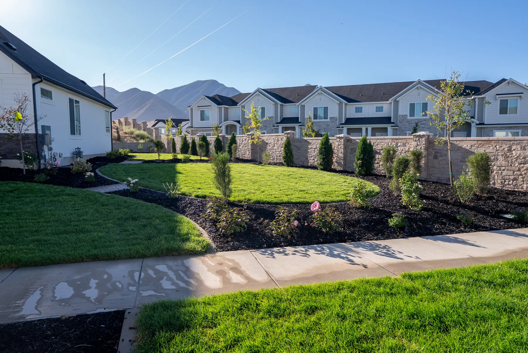 Lawn and beds along a stone wall by J&H Landscaping in Spanish Fork