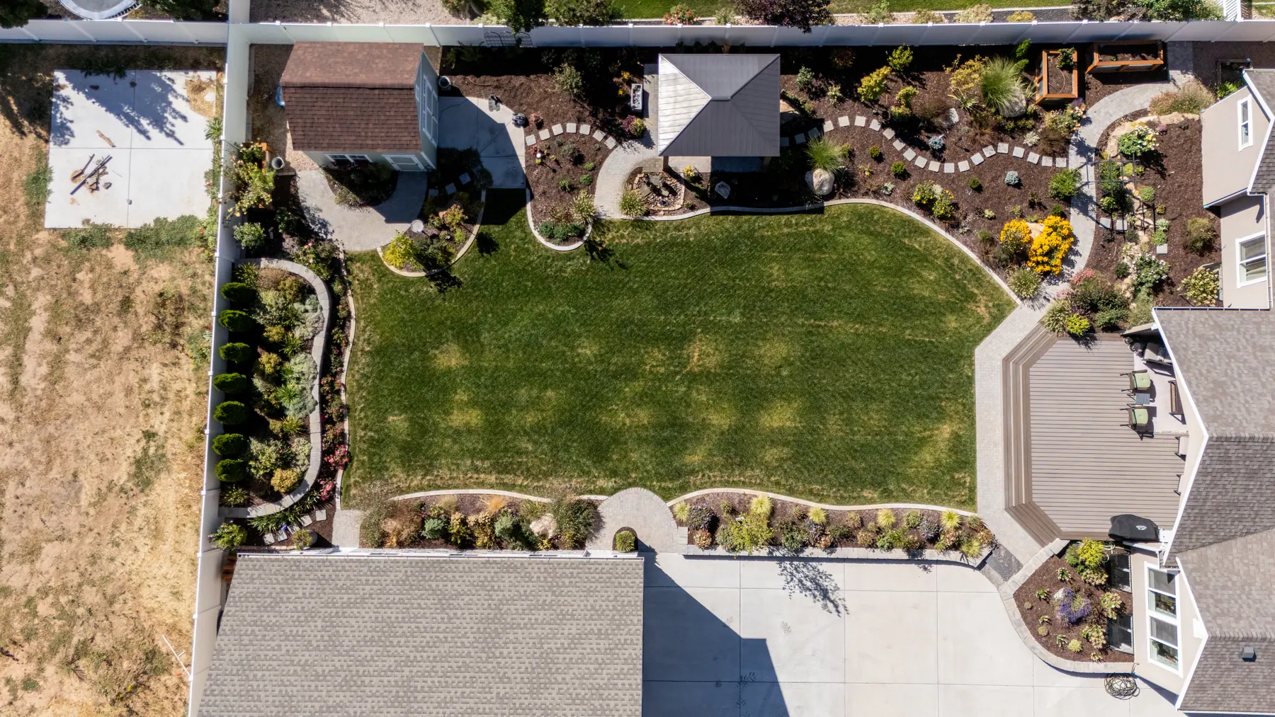 Lawn framed by planting beds by J&H Landscaping in Mapleton