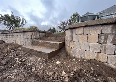 Landscaped stone steps leading to a raised garden wall, showcasing J&H Landscaping's design and construction work in Provo, UT.
