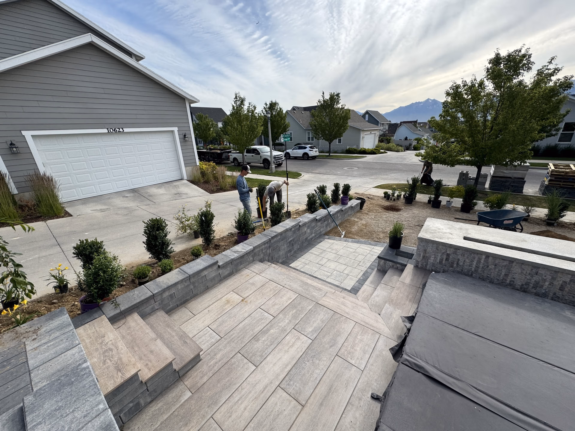Landscaping crew installing durable hardscaping features, including a textured concrete patio and retaining wall, in a residential yard in Spanish Fork, Utah.