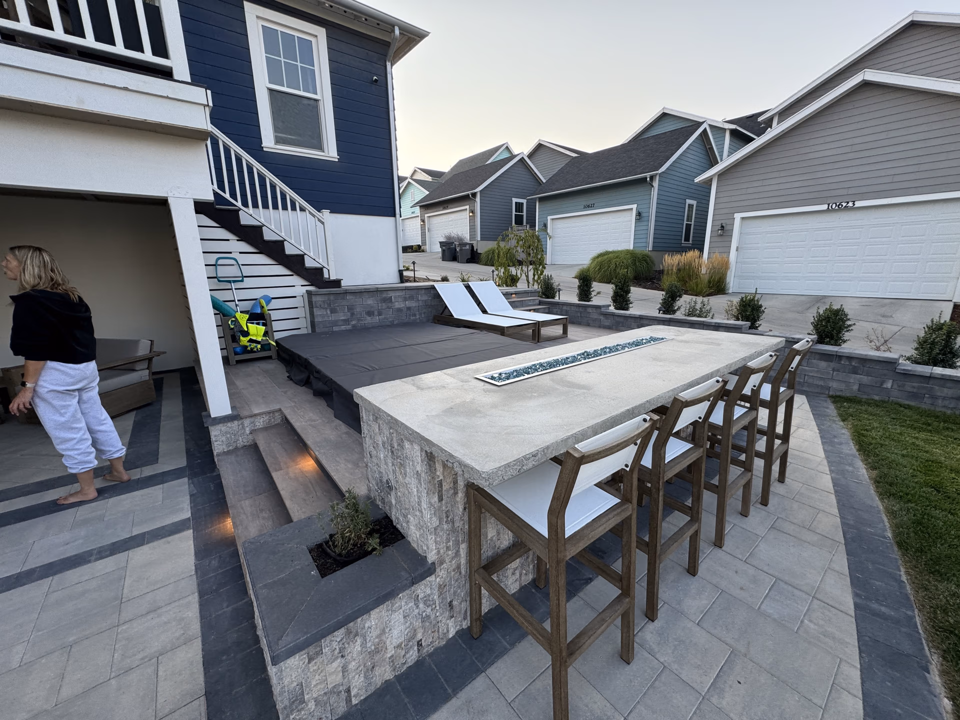 Outdoor hardscaping project featuring a modern patio with seating area, fire pit, and landscaped yard, reflecting durable design for Spanish Fork homes.
