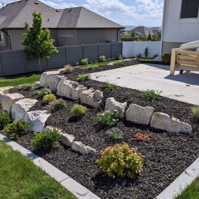 Landscaped yard featuring rock formations, vibrant plants, and well-maintained garden beds, showcasing J&H Landscaping's commitment to clean and finished outdoor spaces in Lindon, Utah.