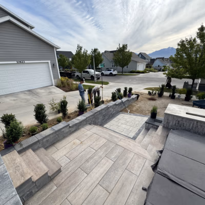 Men working on a concrete patio and hardscaping project in a residential area, showcasing durable outdoor solutions tailored for Mapleton's landscape and climate.