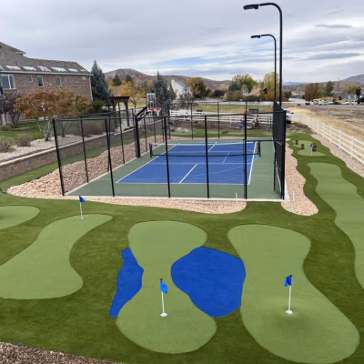 Backyard sports court featuring a pickleball court and basketball hoop, surrounded by landscaped putting greens with flags, designed for multi-sport play in Payson, Utah.