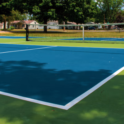 Pickleball court with vibrant blue and green surfaces, featuring a net and clear lines, set in a residential area, emphasizing quality construction for sports activities.