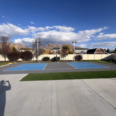 Pickleball court with clean striping and smooth surface, set in a landscaped area with mountains in the background, showcasing J&H Landscaping's quality construction for local conditions.
