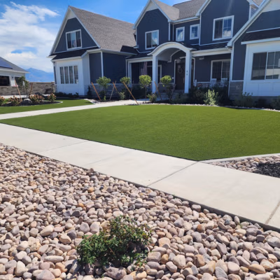 Residential landscaping with well-maintained artificial grass, stone pathway, and modern home exterior in Lindon, Utah, showcasing J&H Landscaping's quality services.